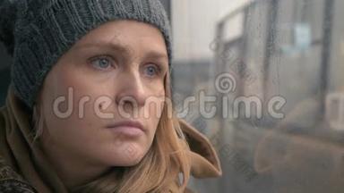 女人凝视着湿漉漉的公共汽车窗户